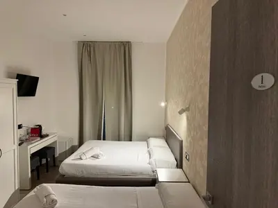 a hotel room with two beds and a desk at Relais Merulana Guest House in Rome