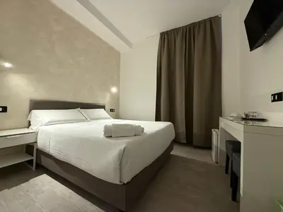 a bedroom with a white bed and a desk and a bed sidx sidx sidx at Relais Merulana Guest House in Rome
