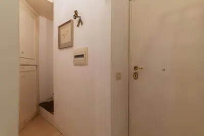 a white hallway with a door and a clock on the wall at GuestHost - Fori Imperiali Pretty Apartment in Rome