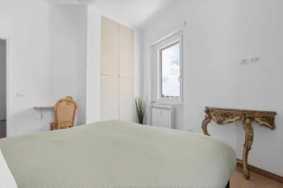 a white bedroom with a bed and a window at Sunny House Gianicolo in Rome