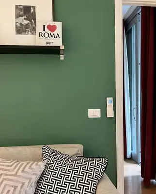 a room with a couch and a green wall at Villa Borghese Green Apartment in Rome