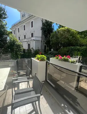 two chairs on a balcony with a building in the background at Villa Borghese Green Apartment in Rome
