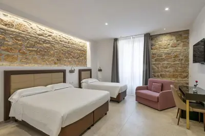 a bedroom with two beds and a stone wall at Joyful 148 Luxury Guest House in Rome