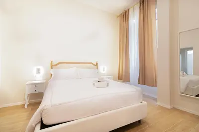 a white bedroom with a large white bed and a mirror at Charme & Chic Nazionale in Rome