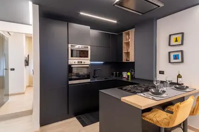 a kitchen with black cabinets and a kitchen island with a stove at Living Testaccio - Modern Apartment in Rome