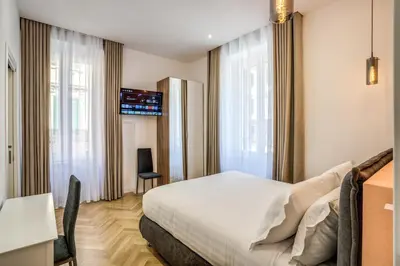 a hotel room with a bed and a desk and windows at Vatican Eagle in Rome