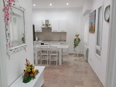 a kitchen with white cabinets and a table with flowers on it at A & F Apartment in Rome