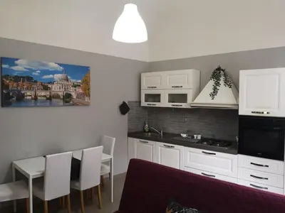 a kitchen with white cabinets and a table and chairs at Gio's home in Rome