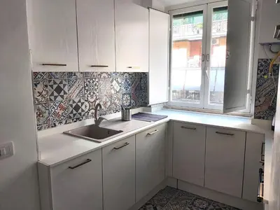 a kitchen with white cabinets and a sink and a window at Roma Furio Camillo Holiday Home in Rome