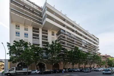 a large white building with cars parked in front of it at GuestHost - Porta Portese Modern Terrace Apartment in Rome