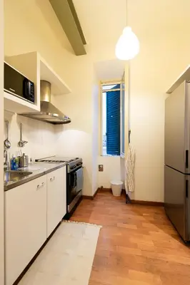 a kitchen with white cabinets and a wooden floor at Yes Holiday Rome in Rome