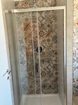 a shower with a glass door and a mosaic wall at Suite and room in Rome