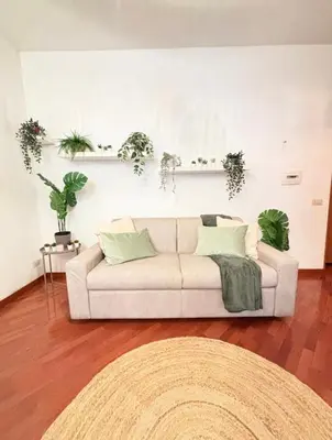 a white couch in a living room with plants on the wall at Saulo Guest House - A 10 minuti da Colosseo in Rome
