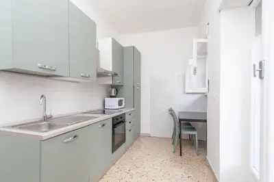 a white kitchen with a sink and a table at via Madonna del Riposo in Rome