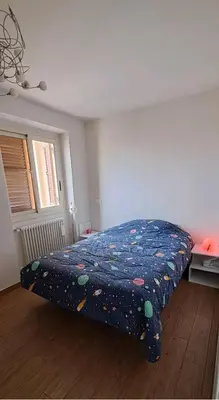 a bedroom with a bed with a comforter on it at Stanza in superattico, terrazzato, luminoso, accogliente, bagno privato in Rome