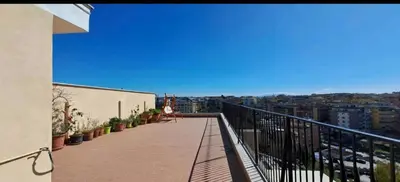 a woman sitting on the balcony of a building at Stanza in superattico, terrazzato, luminoso, accogliente, bagno privato in Rome