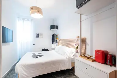 a white bedroom with a bed and a red suitcase at 4BNB - Reale House in Rome