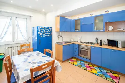 a kitchen with blue cabinets and a table with a colorful rug at 81 mq, Stazione trastevere, Rome Sweet Home in Rome