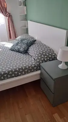 a bed with a gray comforter and a night stand at Roberta Rome Vatican Flat in Rome