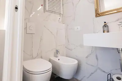 a white bathroom with a toilet and a sink at De Vince Suites - Luxury Rooms - Roma Termini in Rome