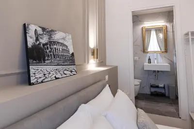 a room with a bed and a bathroom with a mirror at De Vince Suites - Luxury Rooms - Roma Termini in Rome