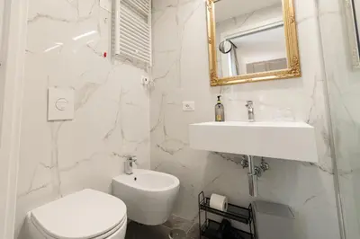 a white bathroom with a toilet and a sink at De Vince Suites - Luxury Rooms - Roma Termini in Rome