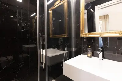 a black bathroom with a sink and a mirror at De Vince Suites - Luxury Rooms - Roma Termini in Rome