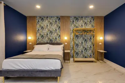 a bedroom with a bed and a blue wall at NAIF Suites in Rome