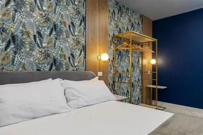 a bedroom with a white bed and a blue wall at NAIF Suites in Rome