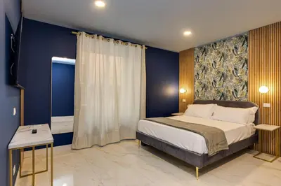 a bedroom with a bed and a blue wall at NAIF Suites in Rome