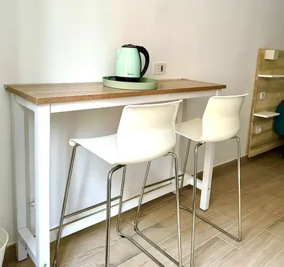 a kitchen counter with white stools and a tea kettle on it at Domus Turno by Local Domus in Rome