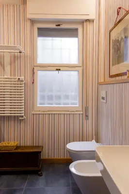 a bathroom with a window and a toilet and a sink at Appartamento Coppedè in Rome