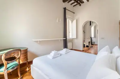 a white bedroom with a bed and a chair at Gn Suite Oro in Rome