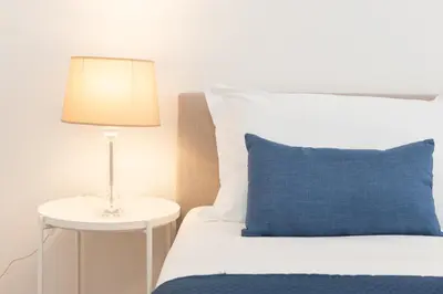 a bed with a blue pillow and a lamp on a table at 25 Penthouse Porta Pia in Rome