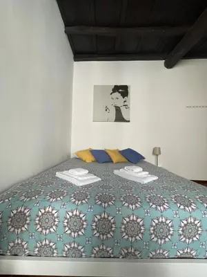 a bedroom with a bed with a blue and white quilt at A Den for Two in Rome