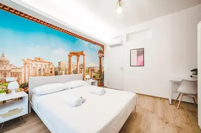a bedroom with a large white bed with a painting on the wall at Tibur Domus B&B in Rome