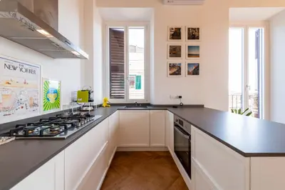 a kitchen with white cabinets and a black counter top at Boho 202 in Rome