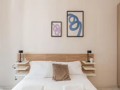 a bedroom with a white bed with two pictures on the wall at The Best Rent - Spacious one-bedroom apartment near Colosseum in Rome