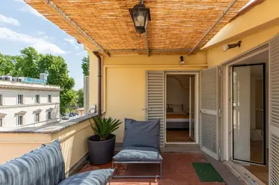 a balcony with a couch and a window at iFlat Trastevere Stylish 4 Bedroom Penthouse in Rome