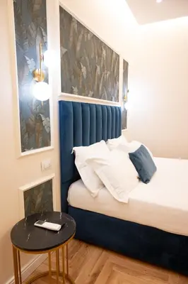 a small bed with a blue headboard and a table at Domus Laurina - Maison D'Art Collection in Rome
