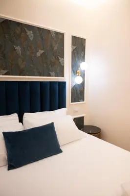 a bedroom with a white bed with a blue headboard at Domus Laurina - Maison D'Art Collection in Rome