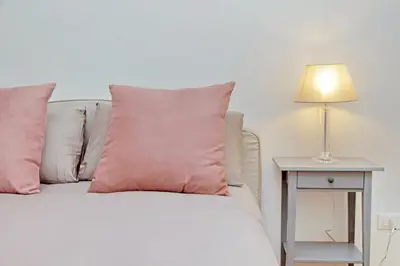 a bed with pink pillows and a table with a lamp at Charme e Style: Splendid Apartment with 2 Bedrooms in Rome
