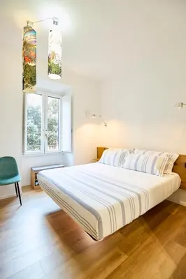 a white bed in a room with a green chair at Casa Cipradino in Rome