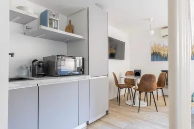 a kitchen with white cabinets and a table with chairs at MauveSweetRhome 3 in Rome