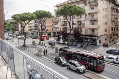 a red bus driving down a city street with cars at Casa Elena - 15 min walk to St Peter's Basilica in Rome