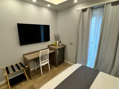 a bedroom with a bed and a desk with a flat screen tv at Niky House Roma in Rome
