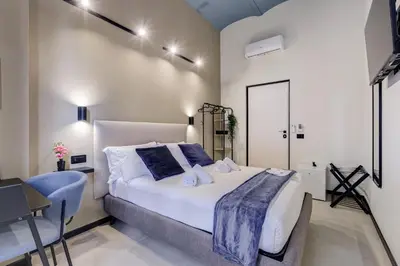 a bedroom with a bed and a table and a chair at VIVILO COLLECTION - Muggia 21 Suites in Rome
