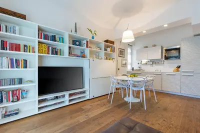 a kitchen and dining room with white shelves and a tv at Elegant Escape near the Vatican in Rome