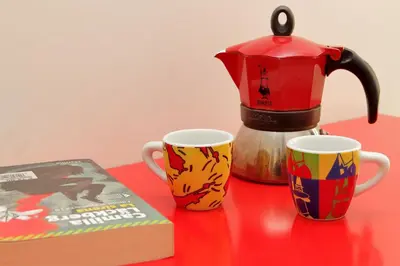 a red table with two coffee mugs and a book at Vatican Claudia's apartment in Rome