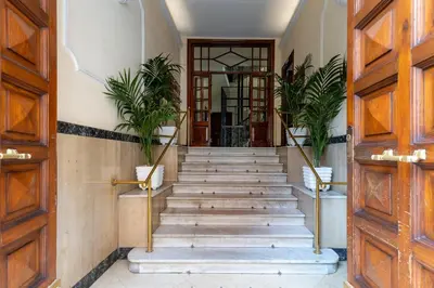 a hallway with wooden doors and stairs with plants at Rome As You Feel - Cozy Open Space Near the Vatican in Rome